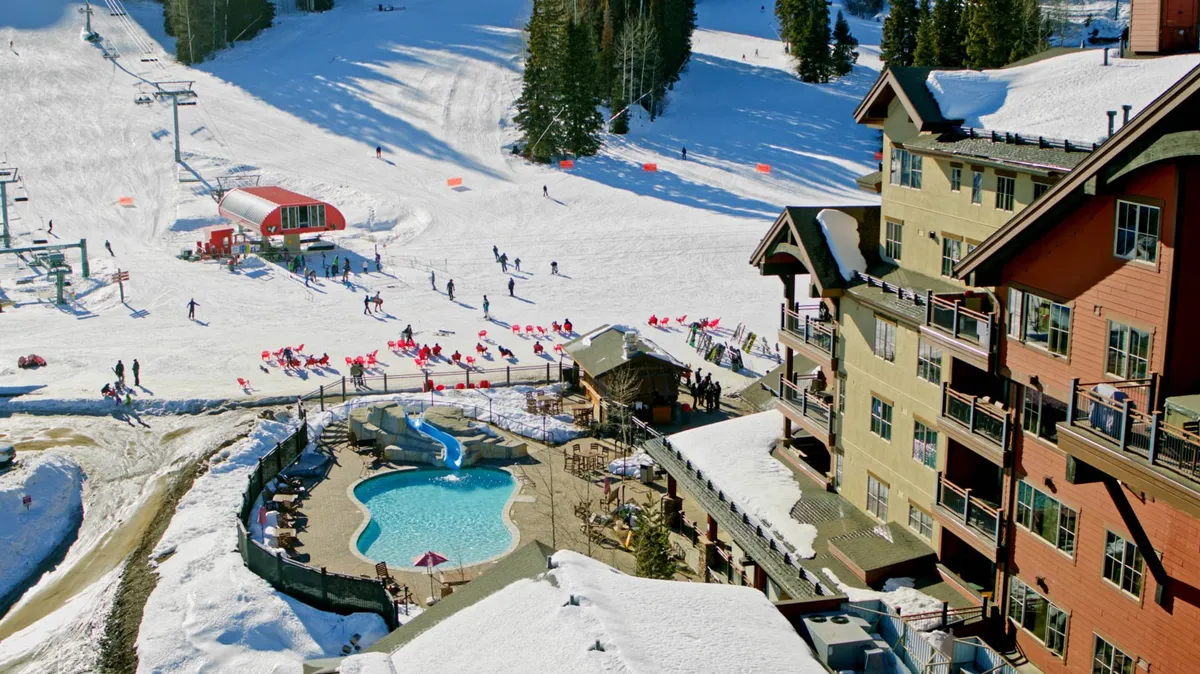 A vibrant exterior scene featuring the ski slopes in action, the resort's swimming pool, ski lift, and hotel exterior. Outdoor seating and groups of guests create a lively, festive mood, while the snow highlights the winter sports atmosphere.