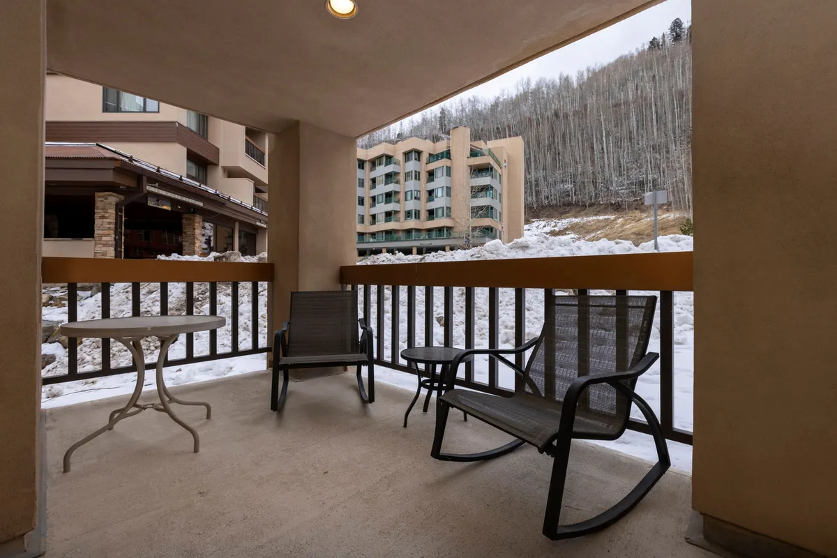 An inviting outdoor space with patio furniture set against a wintry backdrop. Snow covers the ground and surrounding trees, creating a magical atmosphere. The area is ideal for relaxing outdoors with a hot drink or stargazing on crisp evenings, complementing the luxurious retreat theme.